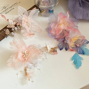 Dettaglio di fermaglio per capelli floreale con petali in mesh, perle e nappine a farfalla