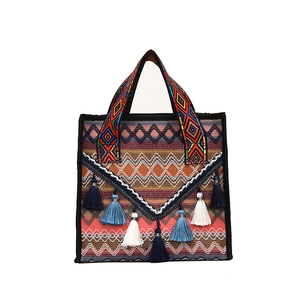 Ethnic style woven bucket bag with vibrant orange and blue patterns and tassels