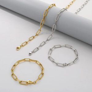 Detail of gold and silver twisted rope paperclip chain bracelets on minimalist props