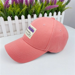 Detail of pink baseball cap featuring a vintage NYC patch with purple text and embroidery