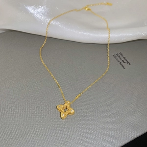 Detailed close-up of textured gold clover pendant with pavé zircon setting and link chain