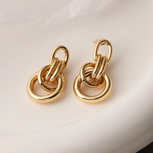 Polished gold geometric multi-ring drop earrings displayed on a white ceramic tray