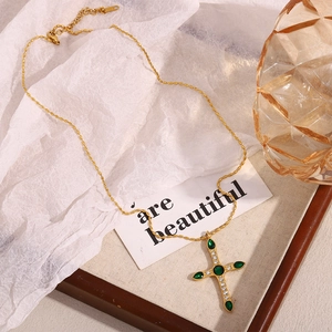 Détail du collier croix plaqué or 18 carats avec zircon vert et gemmes transparentes