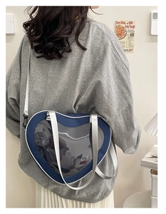 Model wearing dark blue heart-shaped ita bag with clear window and nylon strap