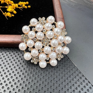 Detail of elegant gold-tone floral brooch featuring white faux pearls and sparkling crystals