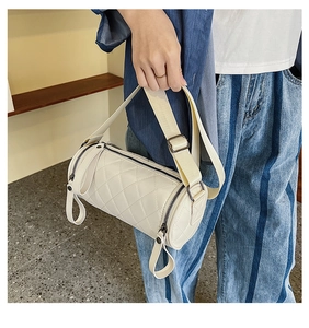 Detail of quilted beige cylinder crossbody bag showing PU leather texture and shoulder strap