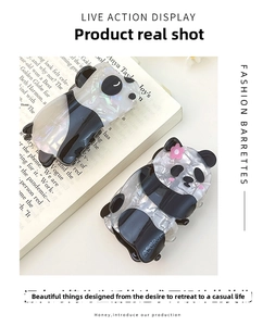 Detail of panda-shaped hair clips in pearlescent acetate on a vintage book background