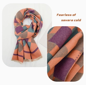 Detail of colorful argyle knit scarf with orange and green patterns and fringed edges