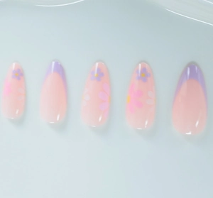 Gros plan d'ongles amande avec pointes french violettes et motifs de fleurs douces