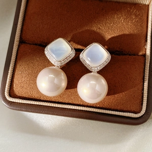 Macro shot of silver pearl drop earrings with square zirconia and soft silk background