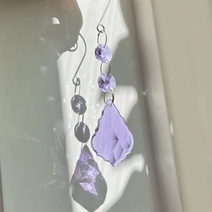 Macro shot of purple faceted crystal suncatcher reflecting light on a neutral background
