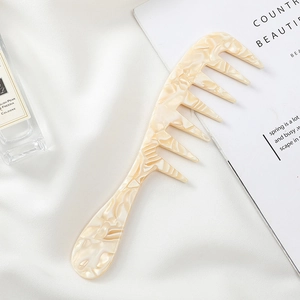 Detailed macro shot of beige marble acetate hair comb on soft white fabric background