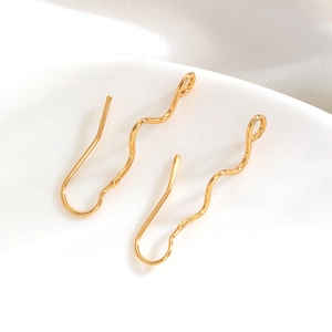Macro detail of golden S-shaped wavy earring hooks with small connection loops