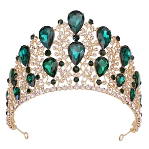 Close-up of Baroque gold crown featuring emerald green teardrop crystals and clear rhinestones