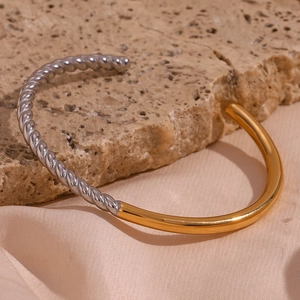Detail of twisted silver texture and polished gold finish on bicolor stainless steel bangle