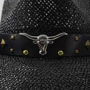 Macro detail of black straw cowboy hat with silver bull head and metal rivets