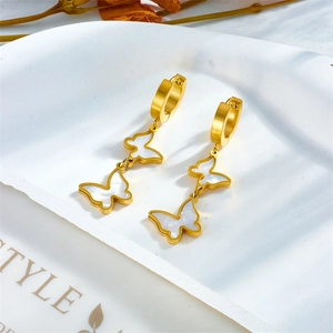 Gold butterfly dangle earrings with white shell inlay on a white decorative tray