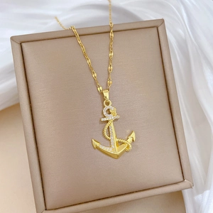 Pendentif ancre dorée avec cristaux sur tissu en soie dans une boîte à bijoux beige