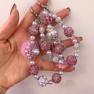 Detail of beaded phone strap with pink rhinestone ball, pearls, and fluffy pom pom
