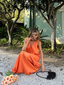 Close-up of orange cotton linen V-neck vest and long skirt set in garden setting