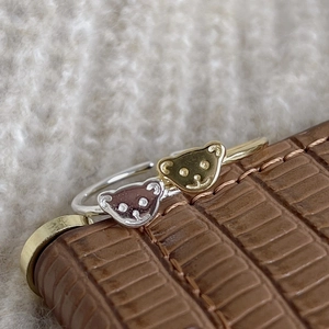 Macro shot of silver and gold bear-shaped open rings on brown crocodile leather base