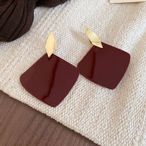 Detail of wine red square resin drop earrings with golden diamond-shaped metal stud