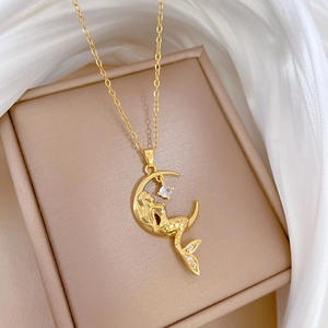 Detailed macro view of gold mermaid and moon pendant with sparkling zircon on satin