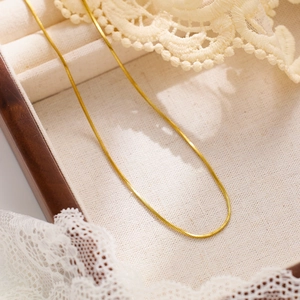 Detailed view of flexible gold snake chain necklace displayed in a vintage jewelry box
