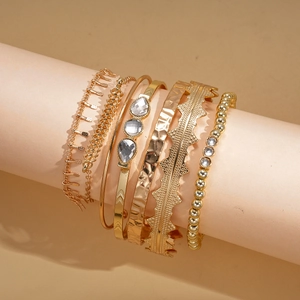 Detail of 6-piece golden bangle set with sparkling rhinestones and hammered textures