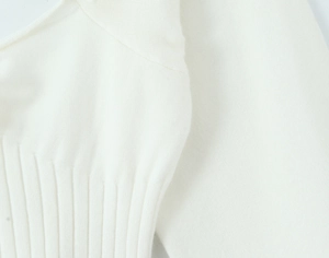 Detailed close-up of white knit fabric texture and ribbed hem on the square neck sweater