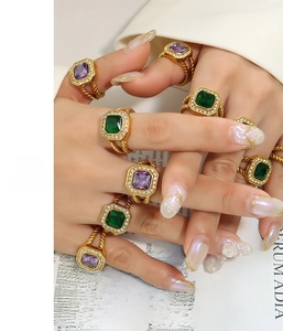 Detailed close-up of gold-plated stainless steel rings with purple and green crystals