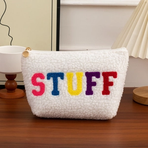 Detail view of plush white fleece makeup bag with colorful STUFF chenille embroidery