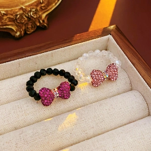Detail of beaded bow rings in black pink and clear crystal inside a velvet jewelry box
