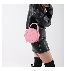 Pink round alarm clock shaped handbag with silver chain strap shown in detail