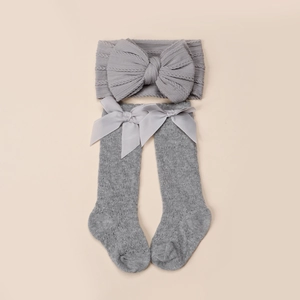 Détail de l'ensemble bandeau et chaussettes de bébé en tricot gris avec grands nœuds