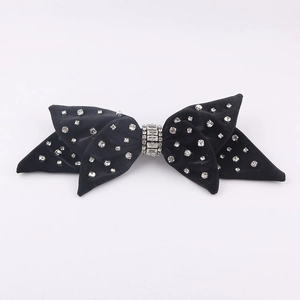 Detailed close-up of a black velvet bow hair claw clip with sparkling rhinestone accents