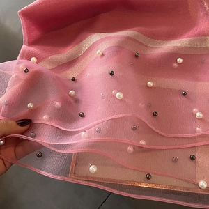 Detail of pink silk-like scarf featuring delicate white pearl beading and gold stripes