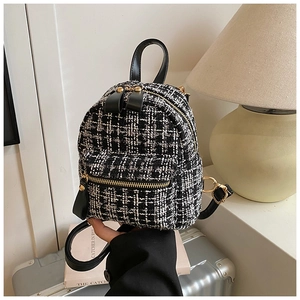 Detail of tweed plaid mini backpack with golden zippers and black leather trim