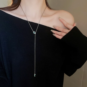 Detail of silver Y-shaped snake chain necklace with green teardrop gemstones on a model