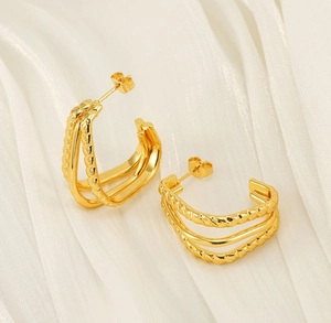 Macro detail of gold layered hoop earrings with twisted rope texture and polished finish