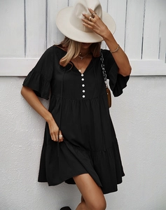 Détail d'une mini robe noire à col en V avec boutons blancs et ourlet à volants