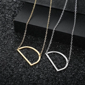 Macro shot of gold and silver letter D pendant necklaces on textured black surface