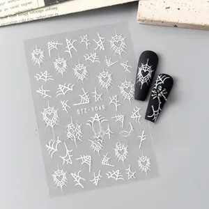 Detail of Halloween nail stickers with white spider web and heart designs on black matte nails