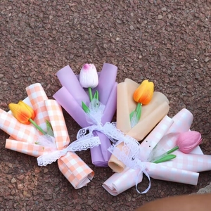 Flat lay of four colorful artificial tulip bouquets with lace ribbons on a textured surface