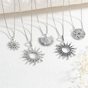 Detail of five punk sun pendants with zircon inlays on textured white background