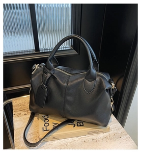 Close-up of black lychee grain texture with double handles and metal zipper on the handbag