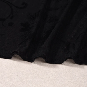 Dettaglio del tessuto a rete nera con eleganti motivi floreali floccati sul vestito