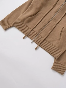 Close-up of brown knitted hoodie texture featuring zipper and ribbed cuff details