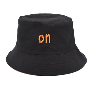 Detailed close-up of a black cotton bucket hat with orange 'on' letter embroidery
