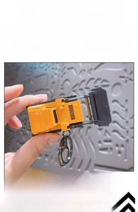 Miniature yellow bulldozer keychain held in hand showing compact portable size